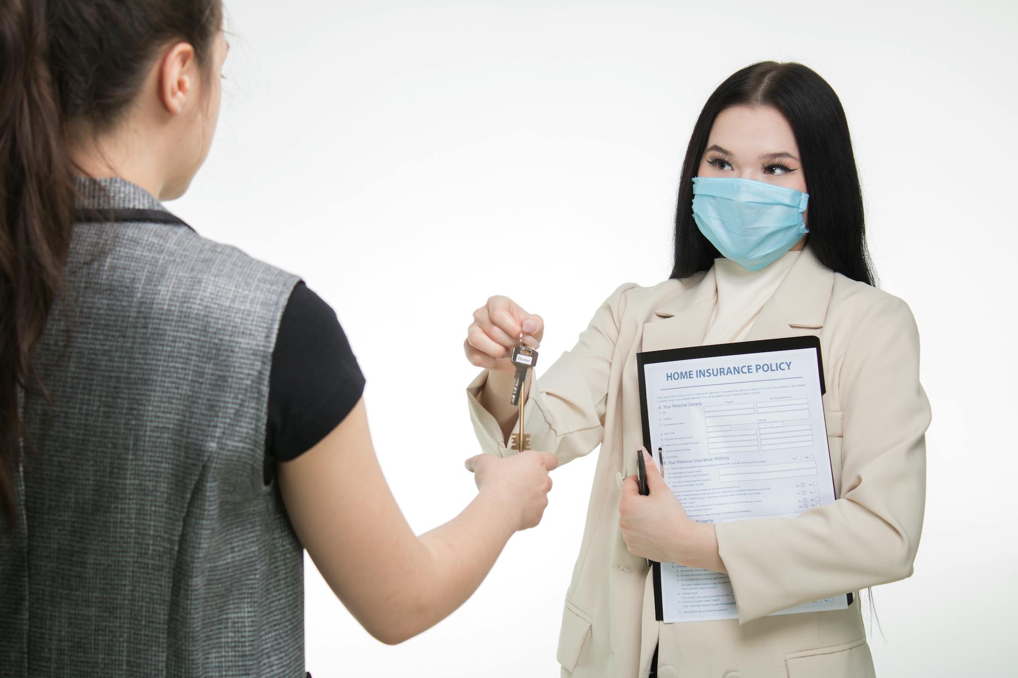 Real estate agent in a face mask hands keys to a client, illustrating safe business practices.